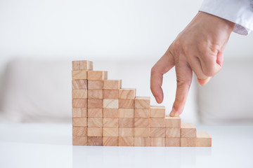 Persons hand walking up a set of wooden blocks. Business development and growth concept