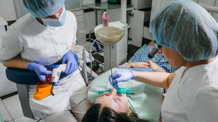 Woman at dentist clinic gets dental treatment to fill a cavity in a tooth. Dental restoration and...