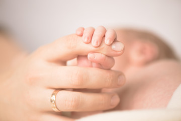Female hand holding her newborn baby's hand. Mom with her child. Maternity, family, birth concept. Copy space for your text
