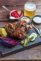 Close view of baked pork knukle with appetizers and beer