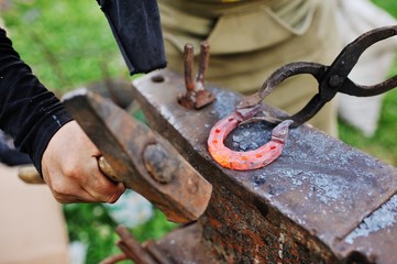 The smith makes a horseshoe on the anvil close-up