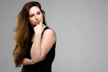 Naklejka premium Emotional pretty confident cute plus size model standing in studio showing her beauty on gray background