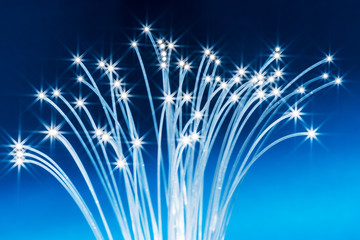 Bundle of optical fibers with lights in the ends. Blue background.