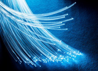Bundle of optical fibers with lights in the ends. Blue background.