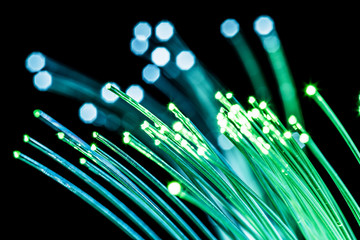 Bundle of optical fibers with green light. Black background.