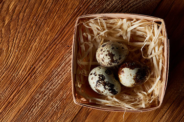 Quail eggs in a box on a rustic wooden background, top view, selective focus.