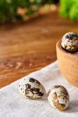 Bowl with eggs quail, eggs on a homespun napkin on wooden table, close-up, selective focus
