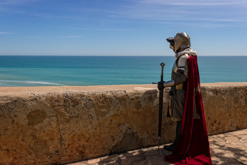 Medieval Templar soldier watches the coastline from the wall