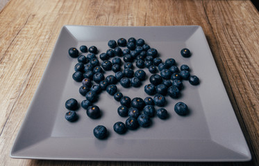 large, fresh blueberries lie on a gray plate, close-up
