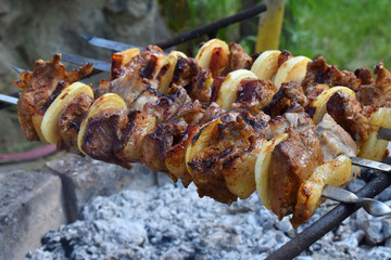 barbecue marinated meat with onion and bacon. Shashlik or Shish kebab preparing on grill over charcoal in nature. Shashlyk skewered meat . BBQ grilling