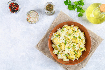 White steamed rice with slices of fried chicken fillet in a bowl on a concrete table. Top view.