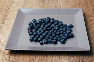 large, fresh blueberries lie on a gray plate, close-up