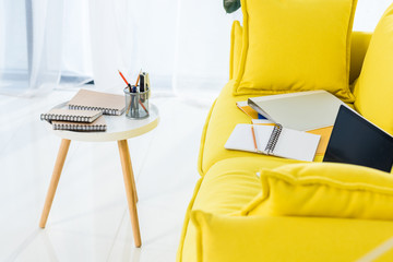 close up view of laptop, notebooks and folders on yellow sofa at home office