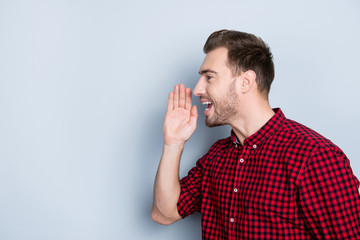 Half-faced side profile view portrait of excited delightful emotional cheerful screaming guy with stylish modern hairdo clothed in red checkered shirt outwear isolated on gray background copy space