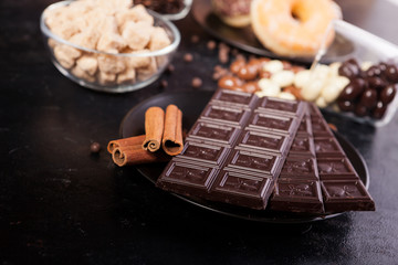 Candies and donuts next to other sweets on dark vintage wooden background