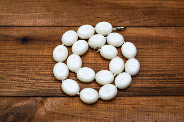 Beads from corals on a wooden background.