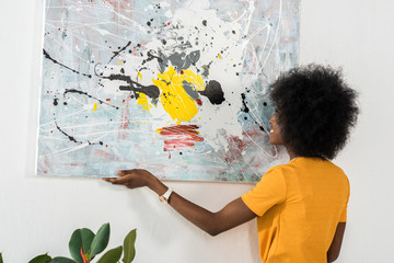 back view of african american hanging picture on wall at home