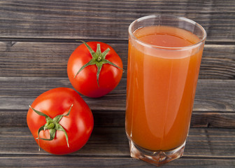 red, juicy, fresh tomatoes and juice on a wooden background