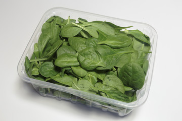 Spinach in a plastic packaging on a white background, ready to sell, Vegan food. Business concept.