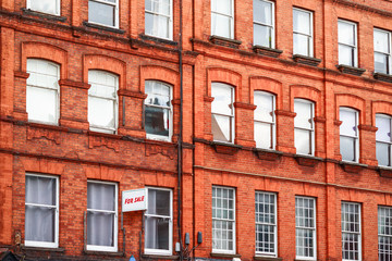 Fototapeta na wymiar Terrace of grand red brick houses with FOR SLAE sign around Camden Town in London