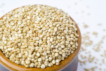 White uncooked quinoa grain in a ceramic bowl, close-up view