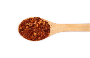 Crushed red cayenne pepper, dried chili flakes and seeds pile in wooden spoon isolated on white background, top view