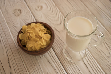 Obraz na płótnie Canvas Delicious corn flakes in a clay bowl with a glass of milk. Rustic wood background. Healthy crispy snack for Breakfast.