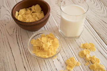 Delicious corn flakes in a clay bowl with a glass of milk. Rustic wood background. Healthy crispy snack for Breakfast.