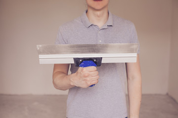 Young worker at work with putty knife