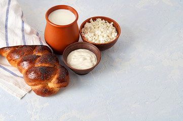 Challah bread with poppy seeds and set of dairy products comprising cottage cheese, sour cream and whole milk