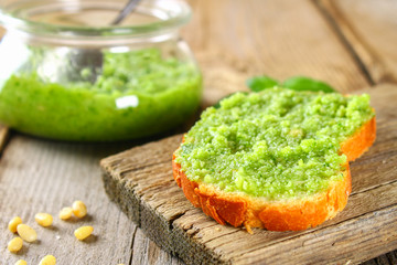 Homemade pesto sauce, bread. Ingredients. Cheese, garlic, basil, pine nuts, olive oil on an old wooden table.