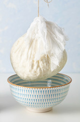 Preparation fresh cottage cheese. The curds in strainer to drain from a wooden spoon between two stacks of glass