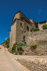Fototapeta na wymiar View of typical stone houses and wall with sunny blue sky, in alley of the historical city center of Gordes. Located in the Vaucluse department, Provence region, southeastern France