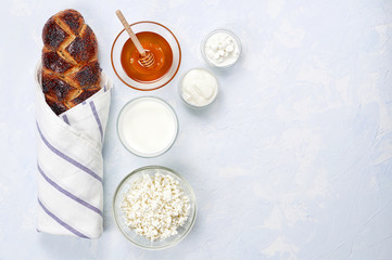 Jewish holiday Shavuot concept. Challah bread with poppy seeds, honey and set of dairy products