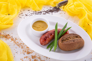 The pork sausage fried on oil is served with mustard sauce and black bread 