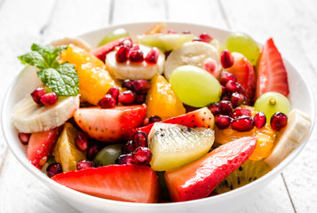 Fototapeta na wymiar Mixed fruit salad on white wooden background