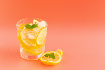 Detox Water with lemon in a glass on an orange background