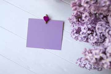 Empty pink blank on and lilac on a white wooden table, top view.