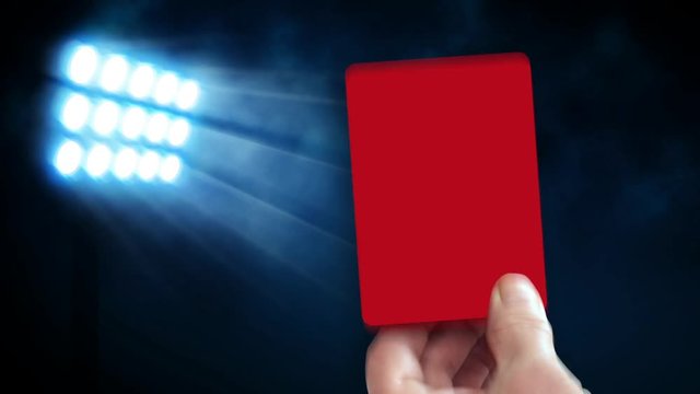 Hand shows red card in front of stadium lights