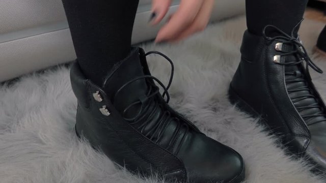 Woman trying on new black boots close up