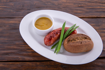 Pork fried sausage in a white plate, is served on a dark wooden background
