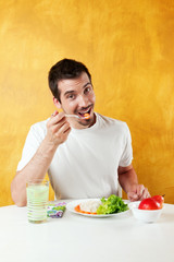 Fototapeta na wymiar attractive young man eating healthy food and looking at the camera