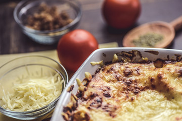lasagne layered served on a wooden board with fresh tomatoes alongside