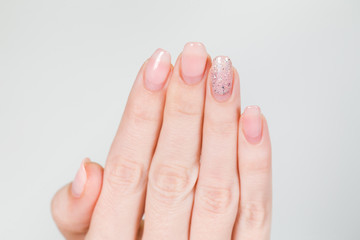 Naklejka premium Closeup of female white hand with old gel polished manicure need correction after several weeks wearing. Horizontal color photography.