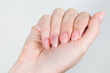 Closeup of female white hand with old gel polished manicure need correction after several weeks wearing. Horizontal color photography.