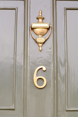 House number 6 sign on green door with brass door knocker