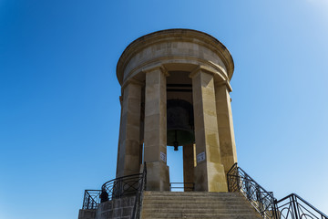 Fototapeta na wymiar Valletta, Malta Siege Bell War Memorial. Large stone bell memorial at the lower part of Saint Christopher Bastion,facing the Grand Harbour in the capital of Malta.