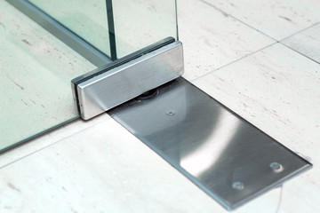 Glass door fittings, swivel mechanism holding the door and allowing the door to turn, metal loop close-up.