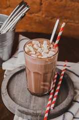 Traditional hot chocolate with marshmallows and candy sticks over white jack towel, dark texture background. Top view glass of cocoa, cinnamon. Christmas drink theme.