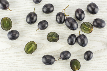 Black grape berries (autumn royal variety) table top isolated on grey wood background some sliced.
